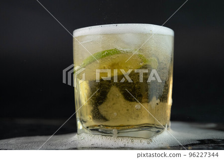 Shot of golden Mexican tequila with lime and salt on black background. A glass of tequila with lemon slices and splashing. Alcoholic drink concept. selective focus. 96227344