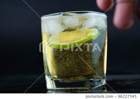 Shot of golden Mexican tequila with lime and salt on black background. A glass of tequila with lemon slices and splashing. Alcoholic drink concept. selective focus. 96227345