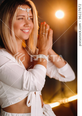 Portrait of a smiling girl in a white dress with her palms clasped in front of her 96227672