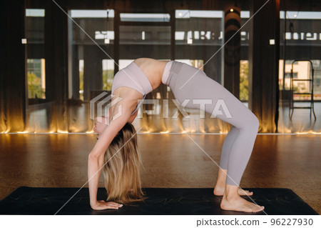 The girl does yoga. A woman in sports clothes does yoga exercises in the gym The girl does yoga. A woman in sports clothes does yoga exercises in the gym 96227930
