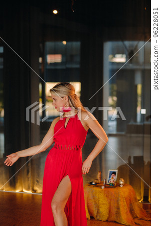 A girl in a red dress moves in a dance meditating indoors . Dynamic dance A girl in a red dress moves in a dance meditating indoors . Dynamic dance 96228051