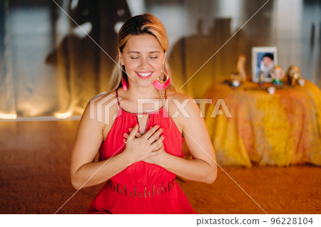 Meditation and concentration. a woman in a red dress, sitting on the floor with her eyes closed, is practicing medicine indoors. Peace and relaxation 96228104