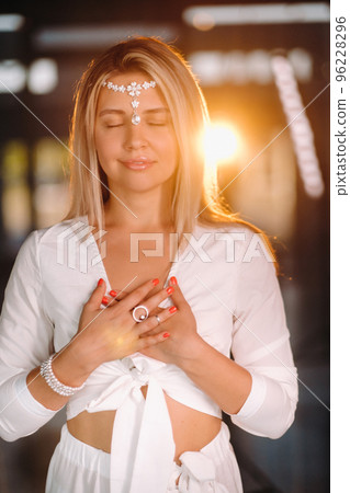 Portrait of a smiling girl in a white dress with her palms clasped in front of her Portrait of a smiling girl in a white dress with her palms clasped in front of her 96228296