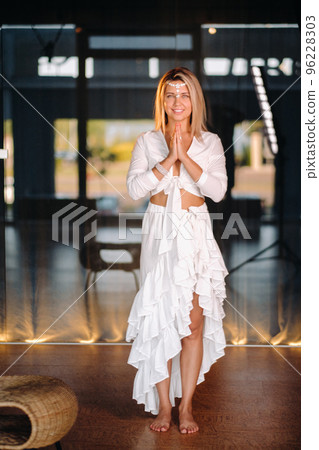 Portrait of a smiling girl in a white dress with her palms clasped in front of her 96228303
