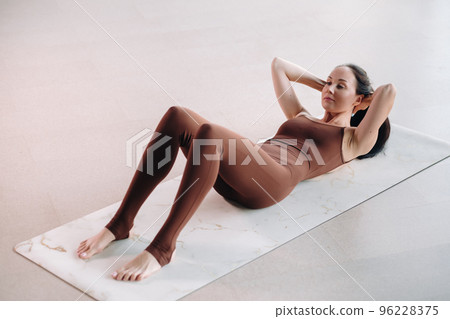 a woman in a brown suit does yoga in a fitness room . Healthy lifestyle, fitness, training, self-care a woman in a brown suit does yoga in a fitness room . Healthy lifestyle, fitness, training, self-care 96228375