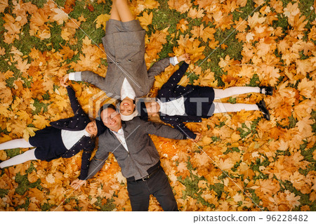 A large family holding hands are lying in an autumn park .Happy people in the autumn park 96228482