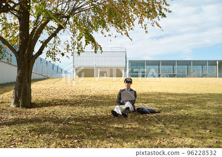 A man sitting on the lawn and using a laptop A man sitting on the lawn and using a laptop 96228532