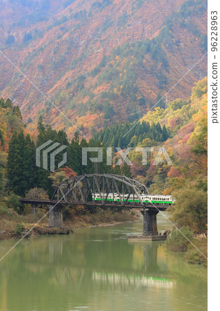 The Tadami Line running over the Tadami River No. 4 Bridge in autumn colors 96228963