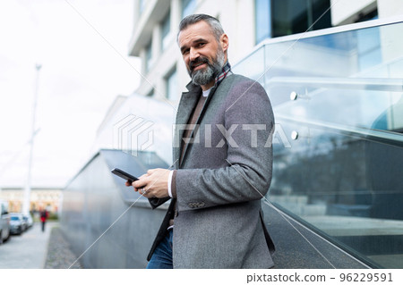 stylish man in business clothes with a mobile phone in his hands outside stylish man in business clothes with a mobile phone in his hands outside 96229591