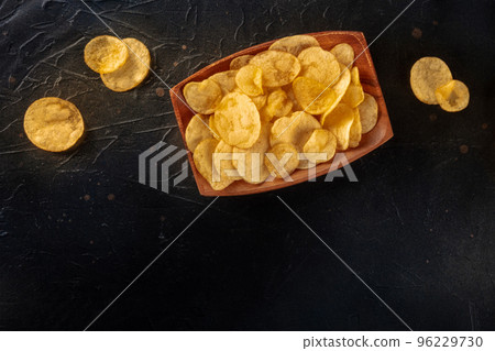 Potato chips or crisps, shot from above on a black slate table 96229730
