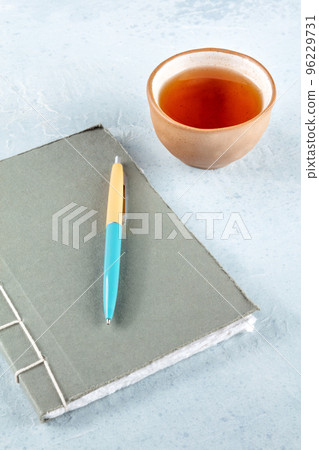 A diary. A paper journal with a pen and a cup of tea on a desk 96229731