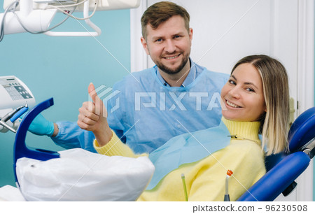 A beautiful girl patient is sitting in the dentist's office at the reception and next to the doctor 96230508