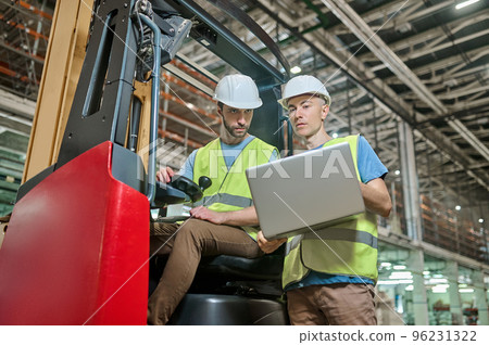 Men in protective helmets working in a storage area Men in protective helmets working in a storage area 96231322