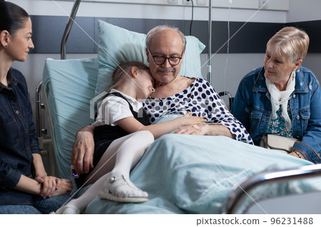 Elderly man in geriatric clinic bedroom hugging little girl. Senior patient relatives visiting medical tower recovery room. Granddaughter visiting sick grandfather at sanatorium. Elderly man in geriatric clinic bedroom hugging little girl. Senior patient relatives visiting medical tower recovery room. Granddaughter visiting sick grandfather at sanatorium. 96231488
