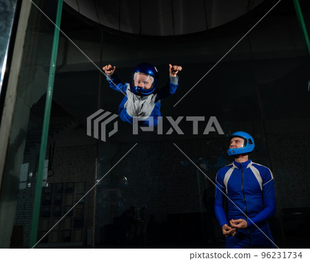 A man teaches a boy to fly in a wind tunnel. Lack of gravity. 96231734