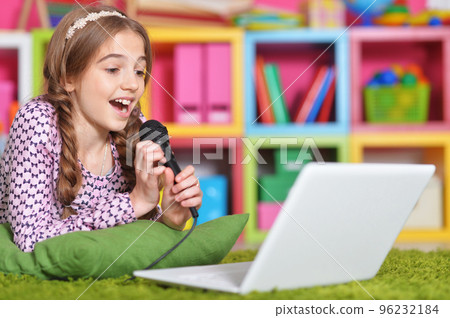 A teenage girl with a laptop sings into a microphone  96232184