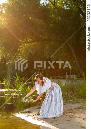 Young beautiful caucasian woman standing at the bank of river. Traditional countryside picture with girl at foreground and copy space. Sun flare Young beautiful caucasian woman standing at the bank of river. Traditional countryside picture with girl at foreground and copy space. Sun flare 96232196