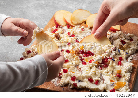 Trendy sweet butter board. Children's hands hold apple slices over the Trendy sweet butter board. Children's hands hold apple slices over the 96232947