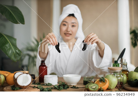 Focus on hands of smiling asian woman holding collagen patches Focus on hands of smiling asian woman holding collagen patches 96234949