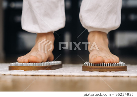 The man's feet are next to boards with nails. Yoga classes The man's feet are next to boards with nails. Yoga classes 96234955