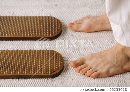 The man's feet are next to boards with nails. Yoga classes The man's feet are next to boards with nails. Yoga classes 96235018