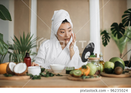 Healthy asian woman preparing cream and applying on face. 96235024