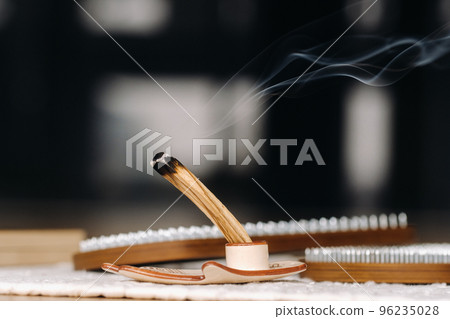 A smoking Palo Santo stick and boards with nails for yoga classes 96235028