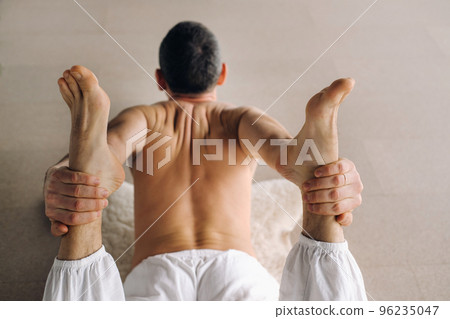 a man with a bare torso does yoga in a fitness room. the concept of a healthy lifestyle a man with a bare torso does yoga in a fitness room. the concept of a healthy lifestyle 96235047