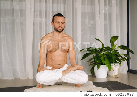 a man with a bare torso does yoga in a fitness room. the concept of a healthy lifestyle 96235088