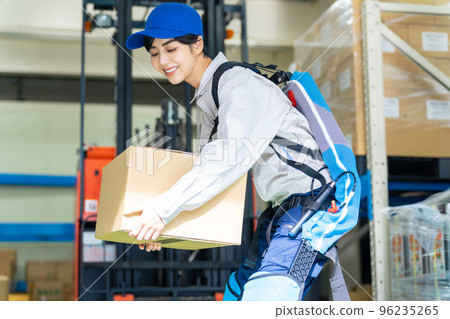 A worker using a power assist suit in a warehouse A worker using a power assist suit in a warehouse 96235265