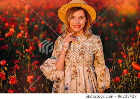 a girl in a dress, in a hat walks in a field with poppies at sunset a girl in a dress, in a hat walks in a field with poppies at sunset 96235427