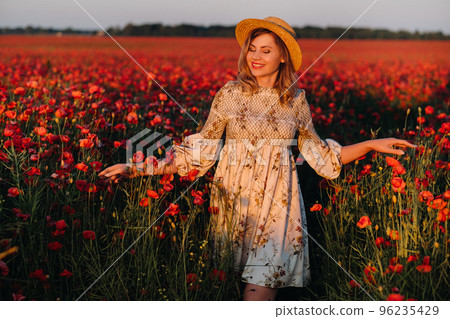 a girl in a dress, in a hat walks in a field with poppies at sunset a girl in a dress, in a hat walks in a field with poppies at sunset 96235429