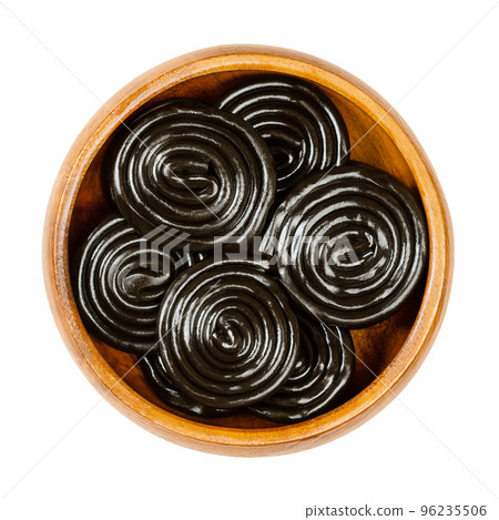 Liquorice wheels, in a wooden bowl. Licorice, is a confection, usually flavored and colored black with the extract of the roots of the liquorice plant Glycyrrhiza glabra, made with sugar and a binder. Liquorice wheels, in a wooden bowl. Licorice, is a confection, usually flavored and colored black with the extract of the roots of the liquorice plant Glycyrrhiza glabra, made with sugar and a binder. 96235506