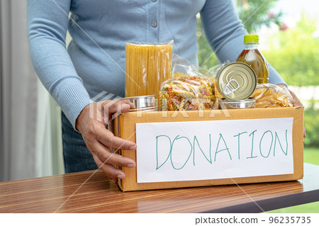 Volunteers putting various dry food in donation box for help people. 96235735