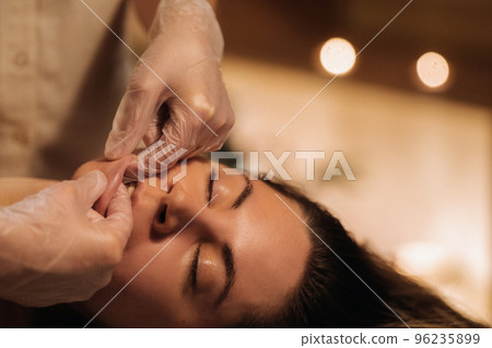 A cosmetologist girl does a facial and neck massage to a girl in the office for skin elasticity A cosmetologist girl does a facial and neck massage to a girl in the office for skin elasticity 96235899