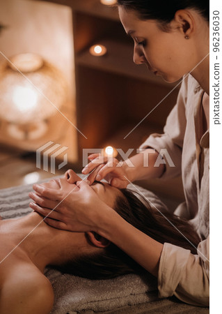 A cosmetologist girl does a facial and neck massage to a girl in the office for skin elasticity 96236030