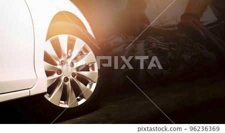 Alloy wheels of the white car are turning on the cement road and engine repairing by auto mechanic 96236369