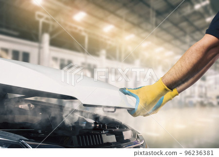 The mechanic opened the hood of the broken car and smoke came from inside the engine compartment The mechanic opened the hood of the broken car and smoke came from inside the engine compartment 96236381