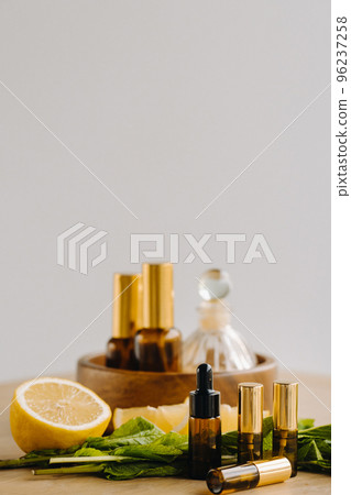 Essential oil in bottles with lemon and mint fragrance lying on a wooden surface 96237258