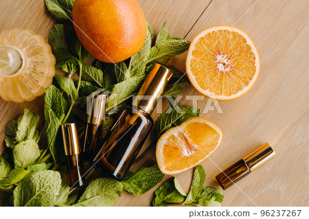 Essential oil in bottles with the aroma of orange and mint lying on a wooden surface 96237267