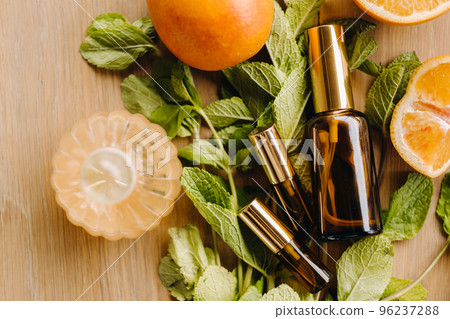 Essential oil in bottles with the aroma of orange and mint lying on a wooden surface 96237288