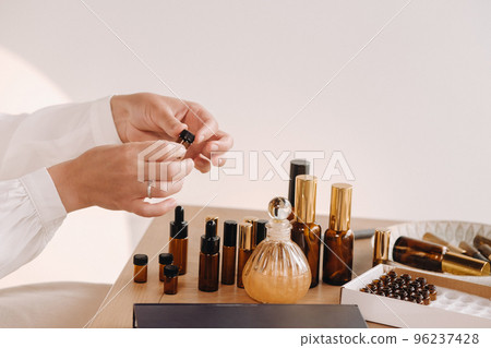 Close-up of a Woman's hands applying essential oil on her wrist indoors Close-up of a Woman's hands applying essential oil on her wrist indoors 96237428