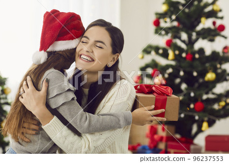 Happy mother gets a present from her loving little daughter on Christmas morning Happy mother gets a present from her loving little daughter on Christmas morning 96237553