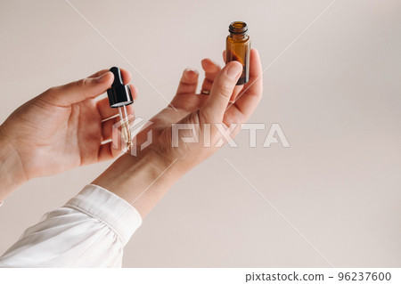 Close-up of a Woman's hands applying essential oil on her wrist indoors Close-up of a Woman's hands applying essential oil on her wrist indoors 96237600