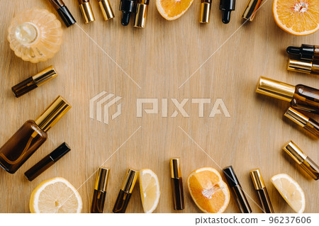 Essential oil in bottles and lemons, oranges lying on a wooden surface Essential oil in bottles and lemons, oranges lying on a wooden surface 96237606
