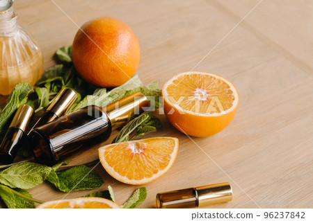 Essential oil in bottles with the aroma of orange and mint lying on a wooden surface 96237842