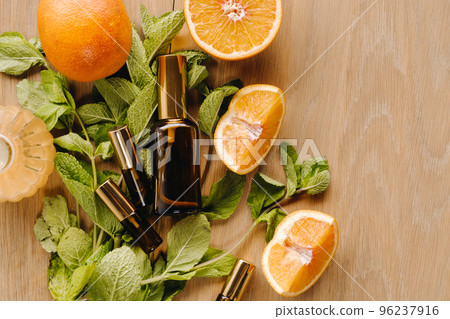 Essential oil in bottles with the aroma of orange and mint lying on a wooden surface 96237916