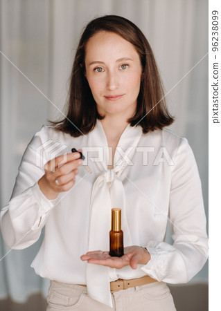 A woman in a white blouse holding a bottle of essential oil, aromatherapy 96238099