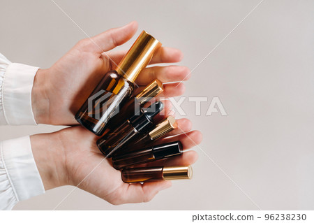 Close-up of female hands holding many bottles of essential oil. Aromatherapy Close-up of female hands holding many bottles of essential oil. Aromatherapy 96238230