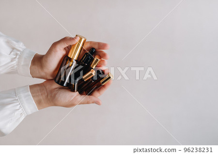 Close-up of female hands holding many bottles of essential oil. Aromatherapy Close-up of female hands holding many bottles of essential oil. Aromatherapy 96238231